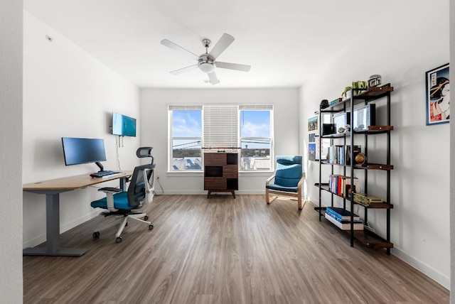 office space featuring a ceiling fan, baseboards, and wood finished floors