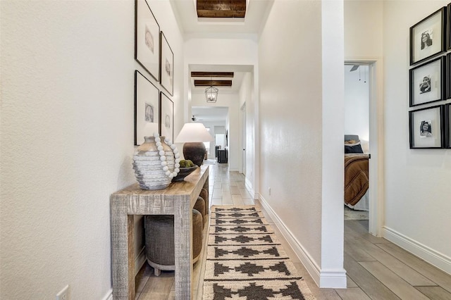 hall with a high ceiling, light wood finished floors, and baseboards