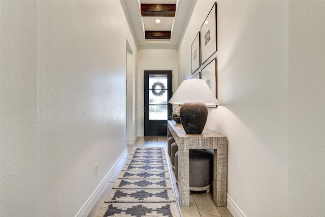 doorway to outside with beam ceiling and baseboards