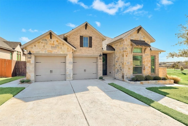 view of front of house with stone siding, fence, and concrete driveway