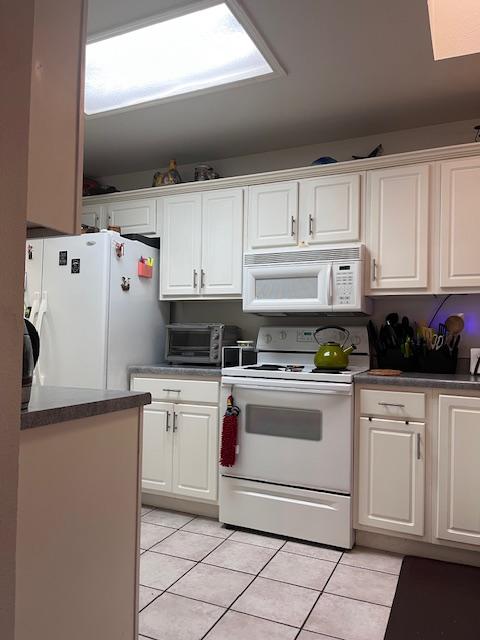 kitchen featuring white appliances, a toaster, white cabinetry, and light tile patterned flooring