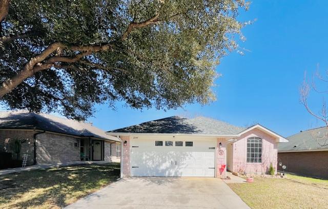 ranch-style house featuring an attached garage, concrete driveway, and a front yard