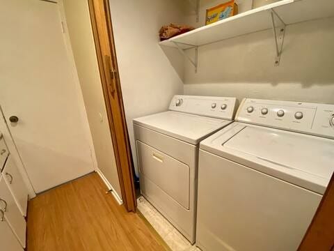 laundry room with laundry area, light wood-type flooring, and washing machine and clothes dryer