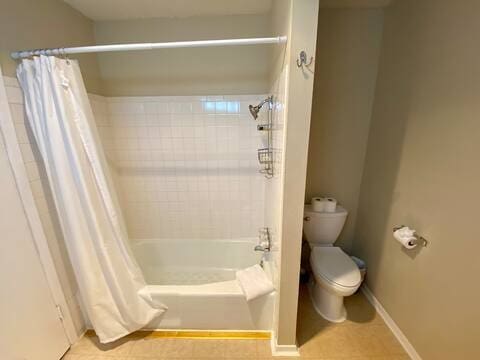 bathroom with shower / bath combination with curtain, baseboards, toilet, and tile patterned floors