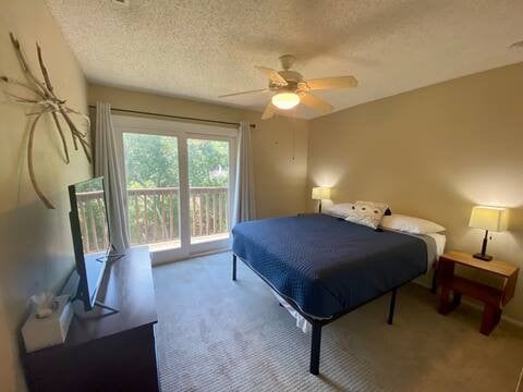 carpeted bedroom with access to exterior, a textured ceiling, and a ceiling fan