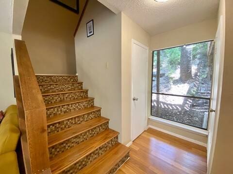 interior space featuring a textured ceiling, wood finished floors, and stairs