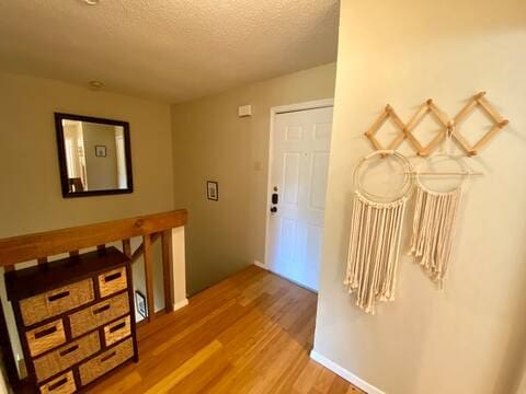 corridor with a textured ceiling and wood finished floors