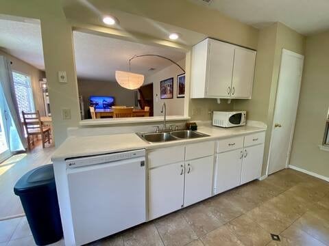 kitchen featuring recessed lighting, light countertops, white cabinets, a sink, and white appliances