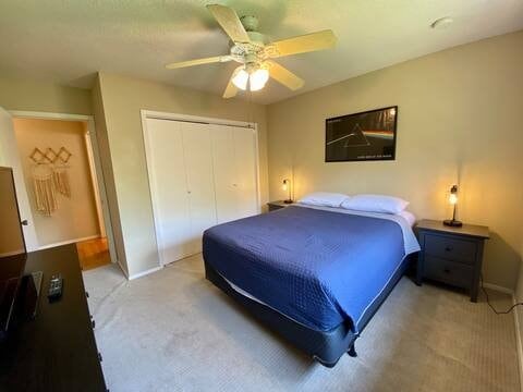 bedroom featuring a closet, light colored carpet, and ceiling fan