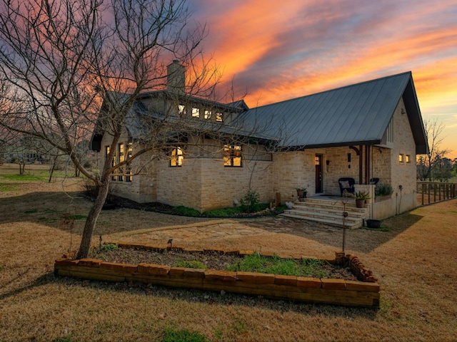 view of front of house featuring metal roof, a porch, a lawn, and stone siding