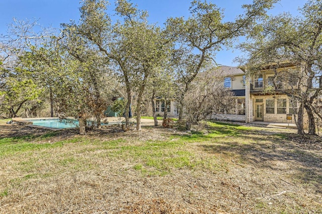 view of yard featuring a patio area, a balcony, and an outdoor pool