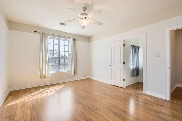 unfurnished room with ceiling fan, baseboards, visible vents, and light wood-style floors