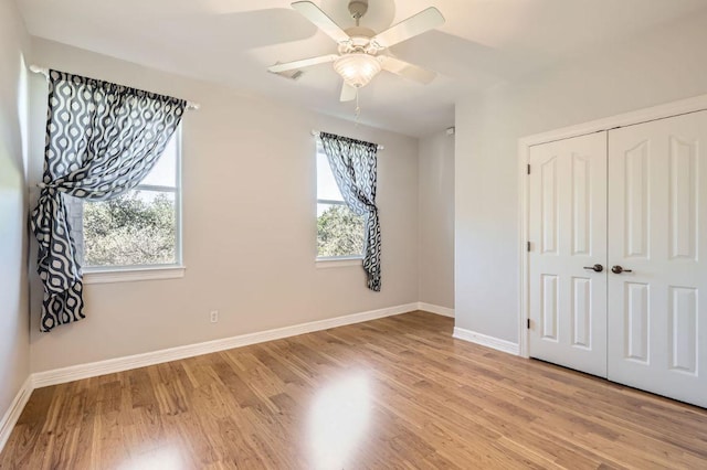 unfurnished bedroom with a ceiling fan, a closet, light wood-style flooring, and baseboards