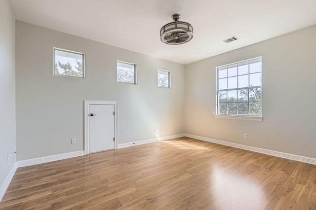 spare room featuring light wood-style flooring, visible vents, and baseboards