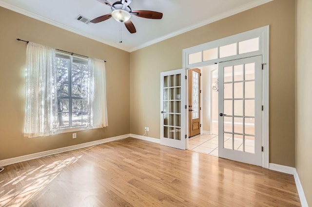 empty room featuring wood finished floors, visible vents, baseboards, ornamental molding, and french doors