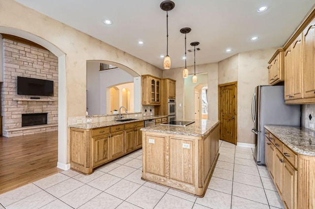 kitchen with a kitchen island, stainless steel appliances, a sink, and light tile patterned floors