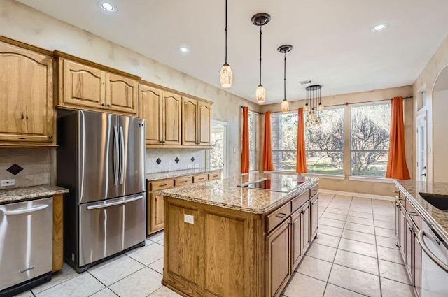 kitchen featuring tasteful backsplash, appliances with stainless steel finishes, a kitchen island, and light stone countertops