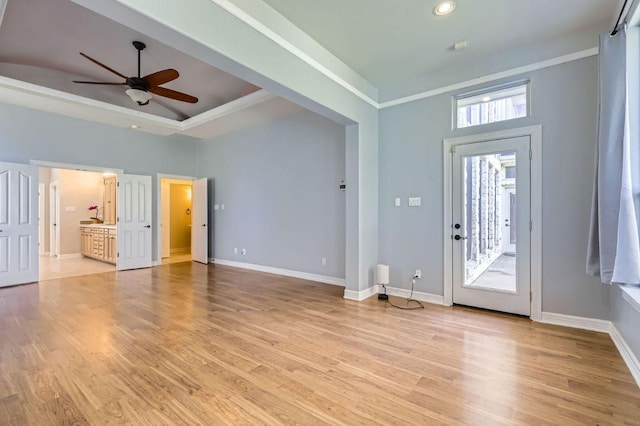 foyer with a raised ceiling, light wood-style flooring, and baseboards