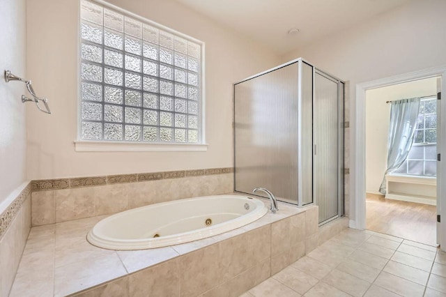 bathroom with a stall shower, tile patterned flooring, and a tub with jets