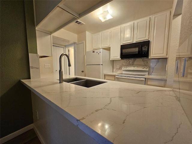 kitchen with a textured wall, light stone counters, white appliances, a sink, and white cabinetry