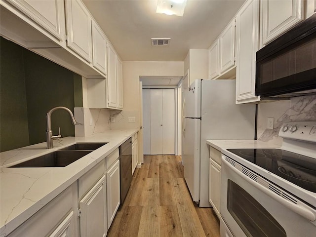 kitchen featuring a sink, visible vents, white cabinets, light wood-type flooring, and black appliances