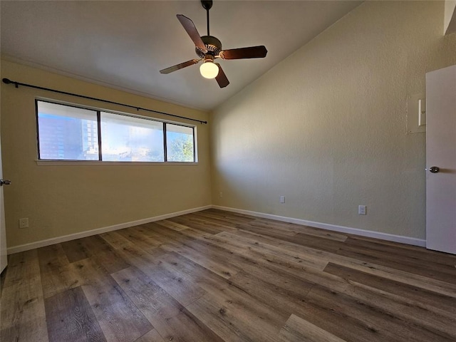 empty room featuring lofted ceiling, a ceiling fan, baseboards, and wood finished floors