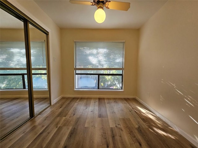 spare room featuring wood finished floors, a ceiling fan, and baseboards