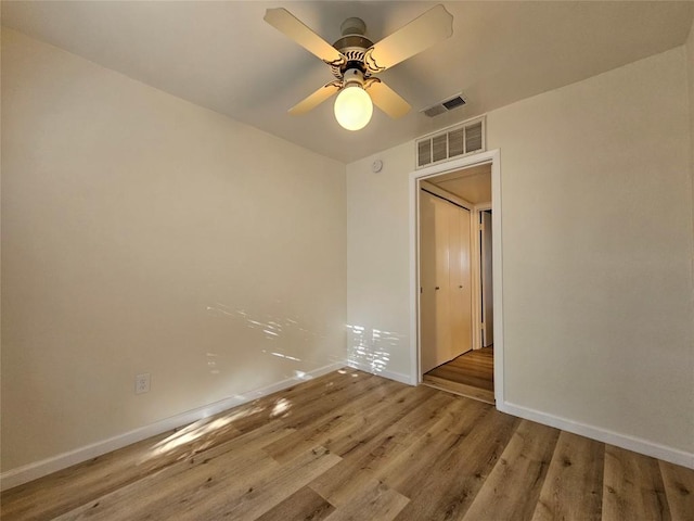 spare room featuring baseboards, visible vents, ceiling fan, and wood finished floors