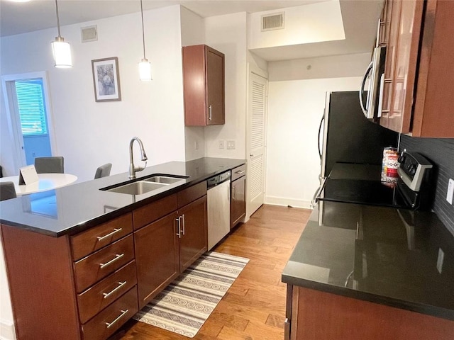 kitchen with light wood finished floors, visible vents, appliances with stainless steel finishes, a sink, and a peninsula