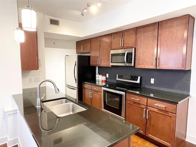 kitchen featuring brown cabinets, visible vents, decorative backsplash, appliances with stainless steel finishes, and a sink