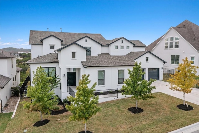 view of front of house with a shingled roof, concrete driveway, a front yard, fence, and a garage