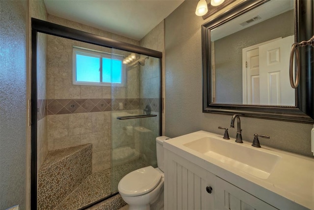 bathroom featuring toilet, a shower stall, visible vents, and vanity