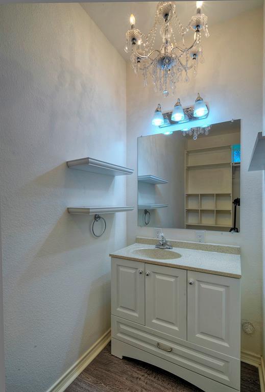 bathroom with a notable chandelier, wood finished floors, vanity, and baseboards