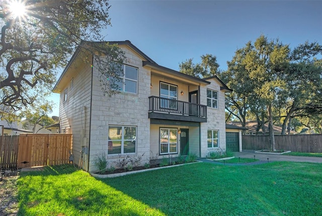 rear view of property featuring stone siding, a yard, and fence