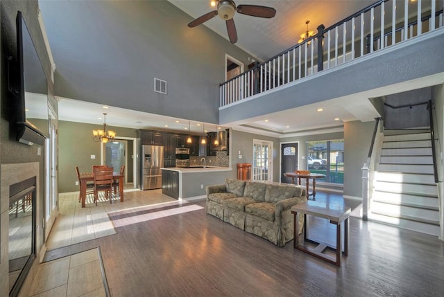 living room with a fireplace, visible vents, wood finished floors, baseboards, and stairs