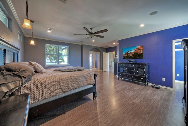 bedroom with arched walkways, wood finished floors, and ornamental molding