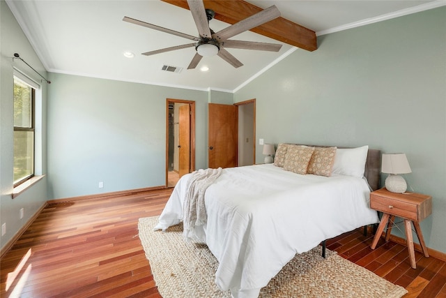 bedroom with lofted ceiling with beams, wood finished floors, visible vents, baseboards, and crown molding