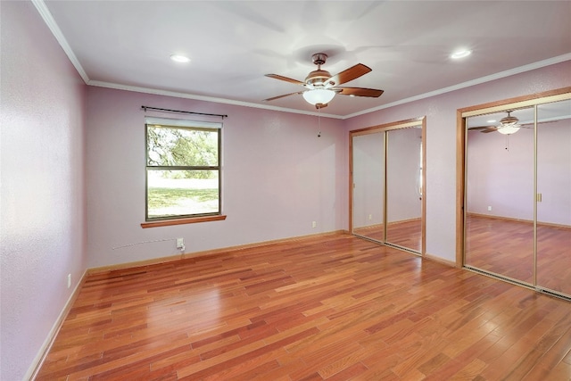 unfurnished bedroom featuring two closets, ornamental molding, ceiling fan, light wood-type flooring, and baseboards