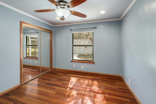 empty room with crown molding, baseboards, and hardwood / wood-style floors