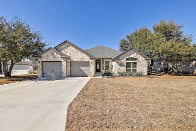 french provincial home featuring an attached garage, stone siding, a front lawn, and concrete driveway