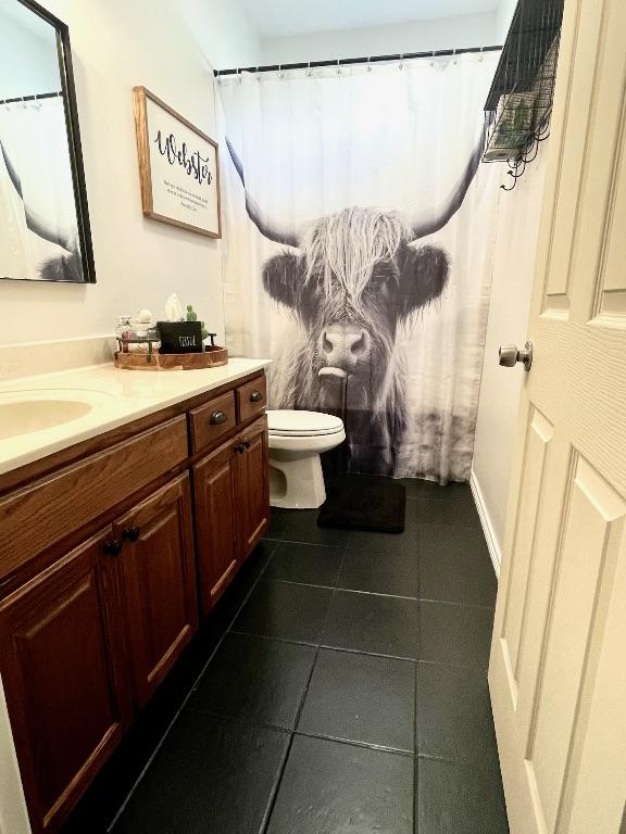 bathroom with toilet, tile patterned flooring, and vanity