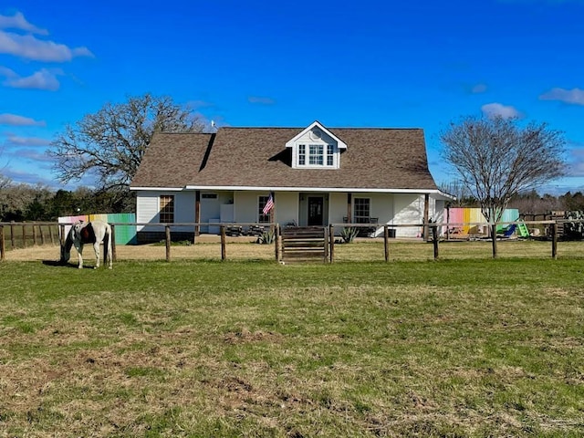 rear view of house with a shingled roof, fence, and a yard