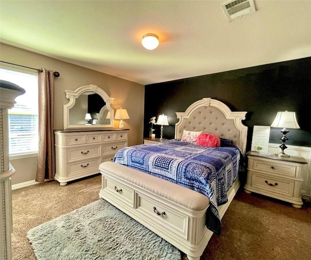 bedroom with baseboards, visible vents, an accent wall, and carpet