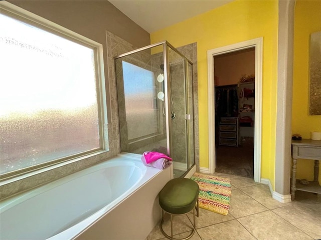 full bathroom featuring baseboards, a garden tub, tile patterned flooring, a spacious closet, and a shower stall