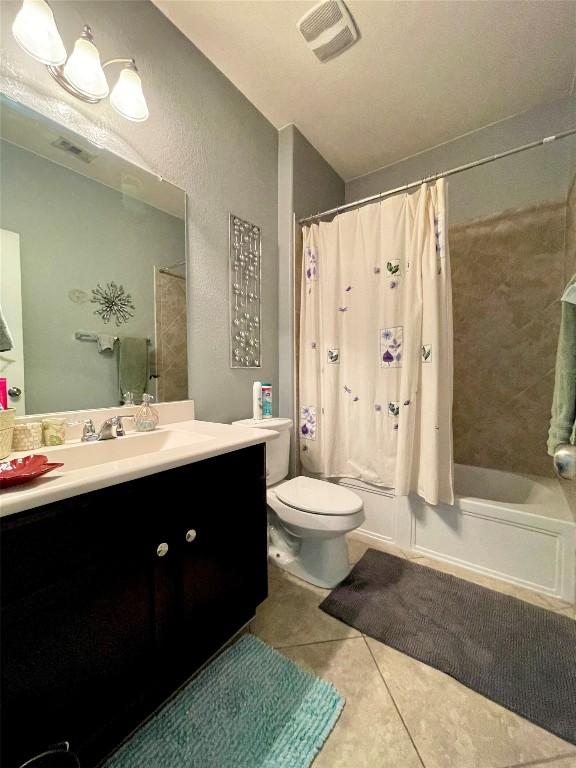 bathroom featuring visible vents, toilet, shower / tub combo, vanity, and tile patterned flooring