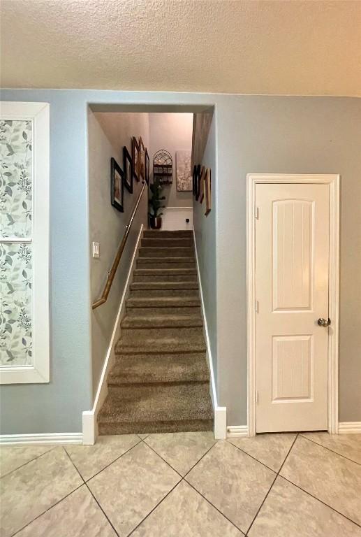 stairs featuring a textured ceiling, baseboards, and tile patterned floors