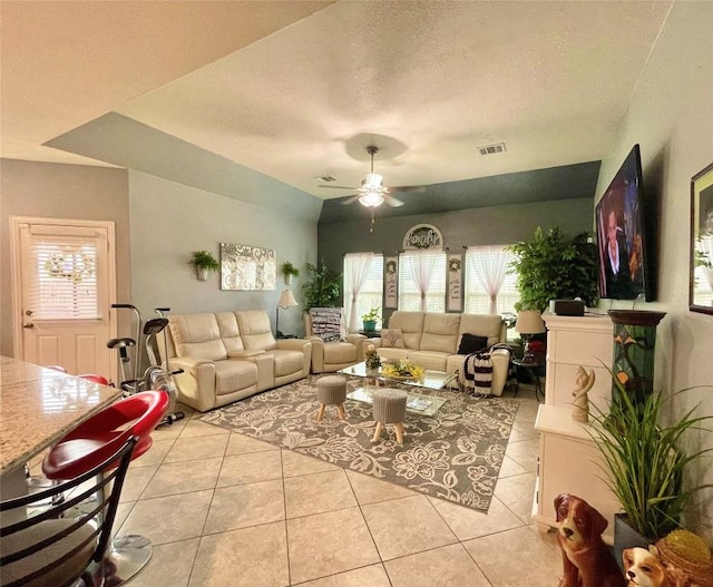 living room with a ceiling fan, visible vents, a textured ceiling, and light tile patterned flooring