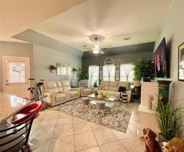 living room with light tile patterned flooring, a textured ceiling, visible vents, and a ceiling fan