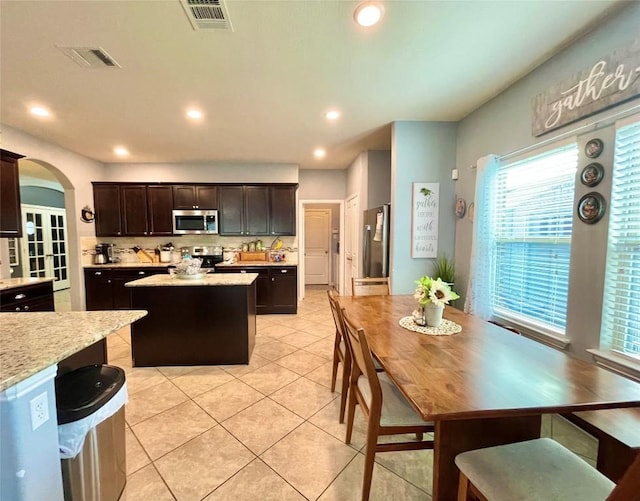 kitchen featuring visible vents, stainless steel appliances, arched walkways, and a center island