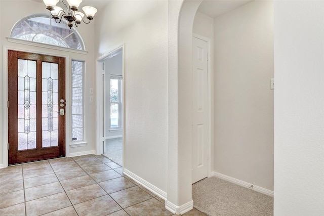 entrance foyer with light tile patterned floors, baseboards, arched walkways, and an inviting chandelier